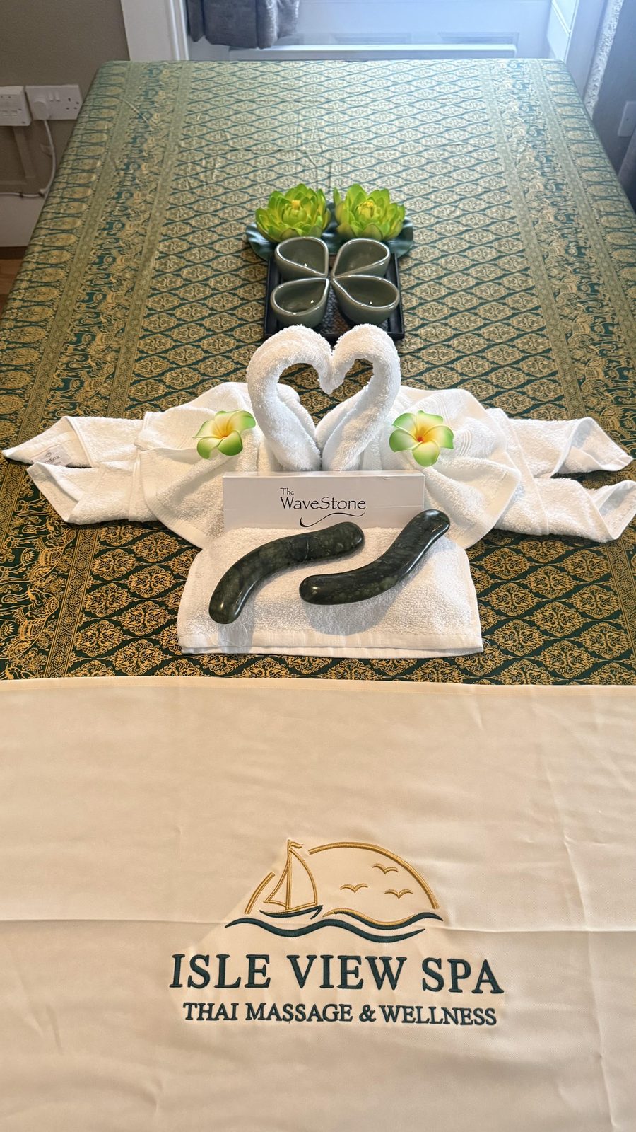 A treatment bed made up with towels and jade massage stones, ready for a hot stone treatment